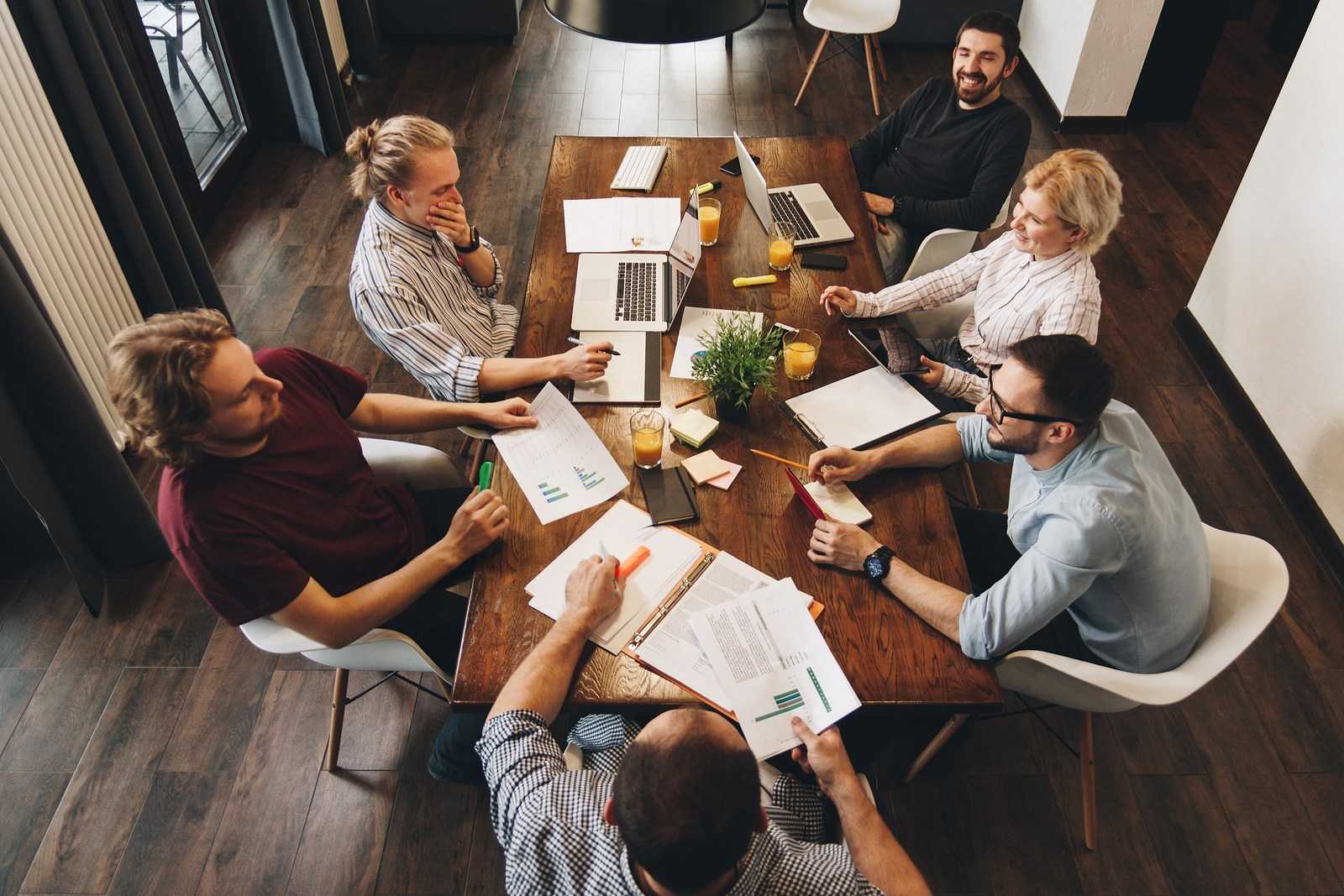 Photo on top of group of young business team working together on new project. Teamwork of creative managers in loft space. Concept of work in modern office on laptops and tablets